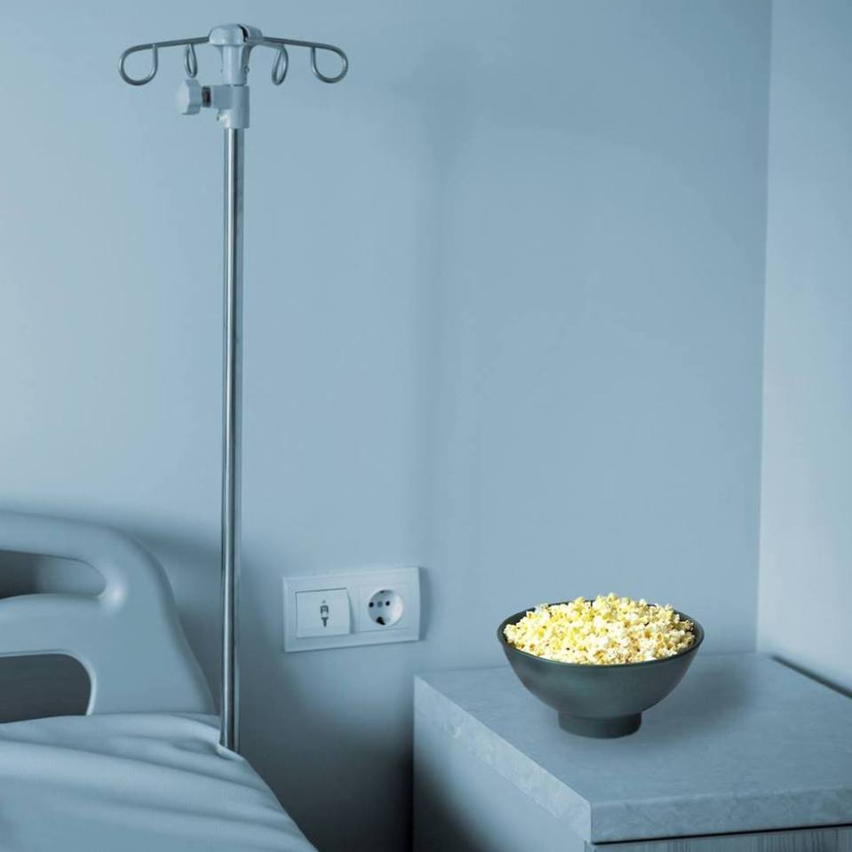 Empty hospital bed with bowl of popcorn on the stand
